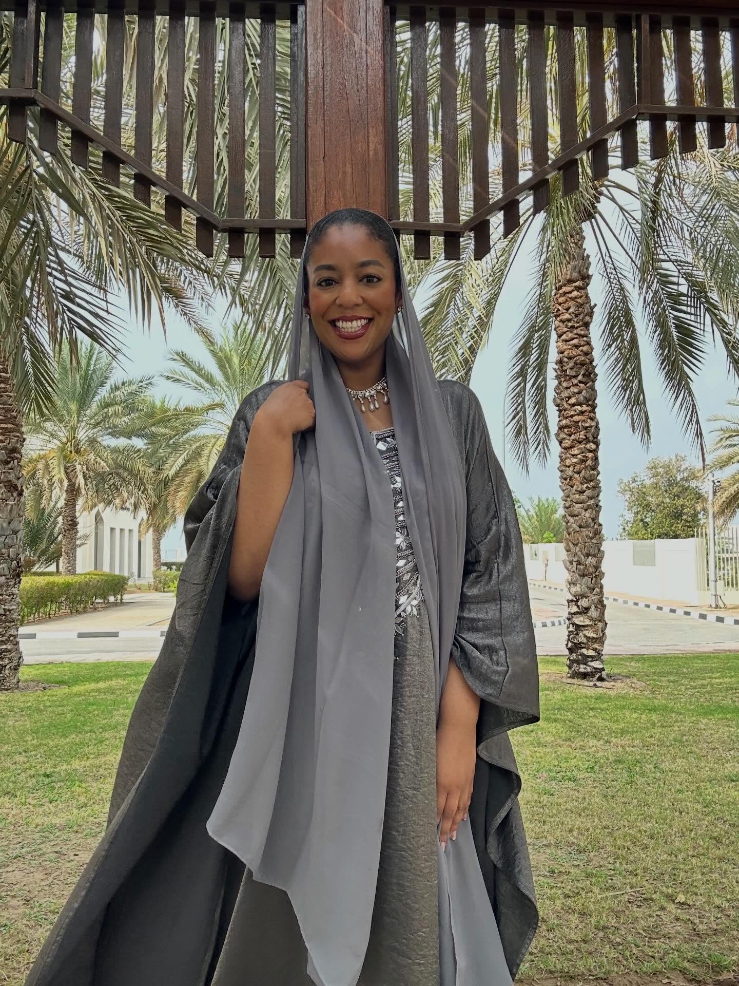 Asma in a grey abaya under the palms